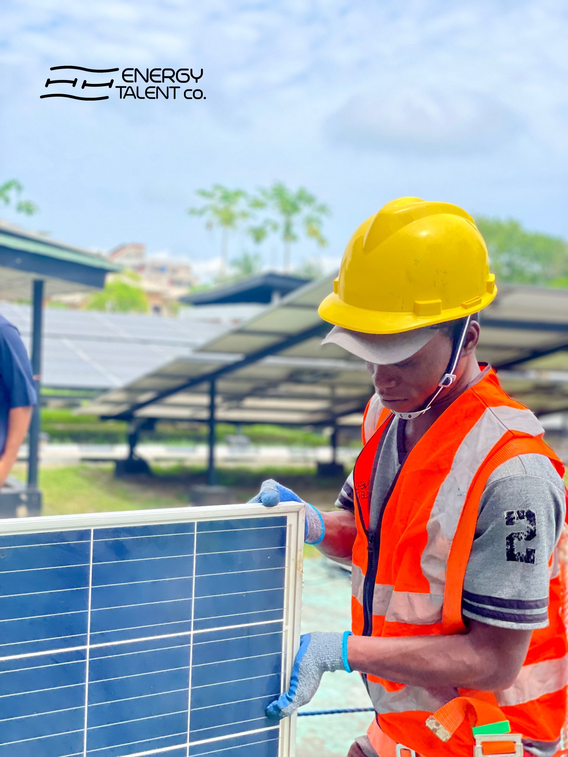 A solar engineer on a site carrying a solar panel.